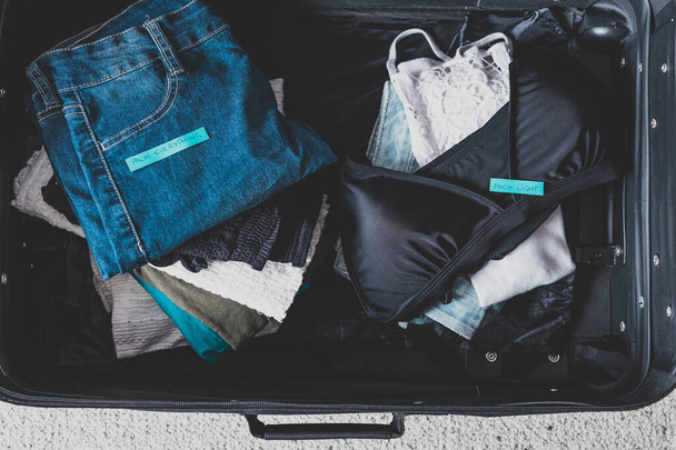 luggage with two pile of clothes and Packing Everything vs Pack  - Фото, зображення