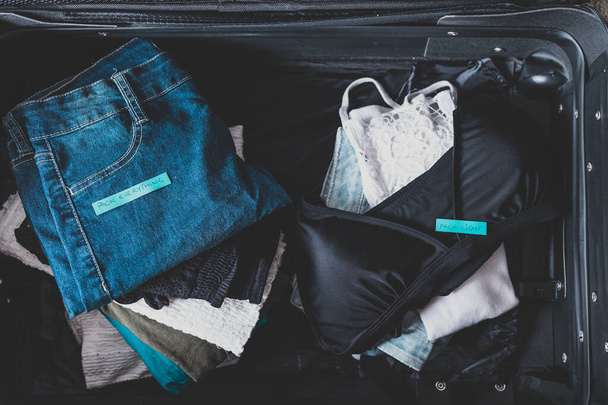 luggage with two pile of clothes and Packing Everything vs Pack  - Фото, изображение
