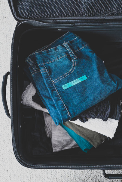 luggage with pile of clothes and Packing Everything label on the - Фото, изображение