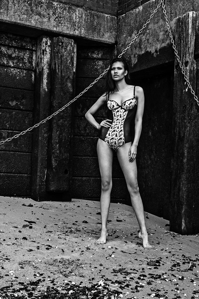 Білизна бікіні молода сексуальна латиноамериканська фотомодель позує на пляжі поруч зі старою брудною стіною
 - Фото, зображення
