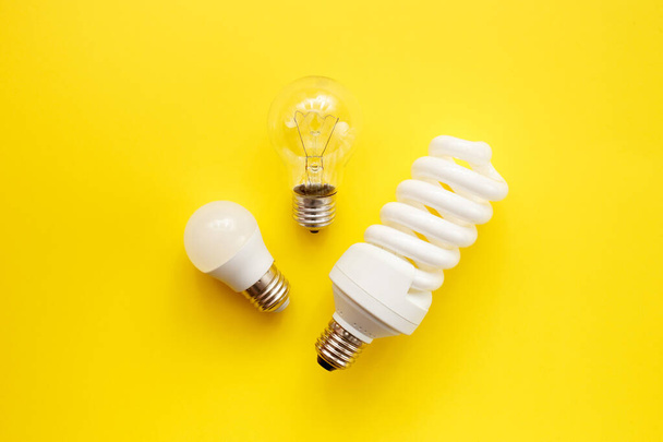 LED lamp, fluorescent and incandescent on a yellow background. Top view, flat lay. Choice concept. - Photo, Image