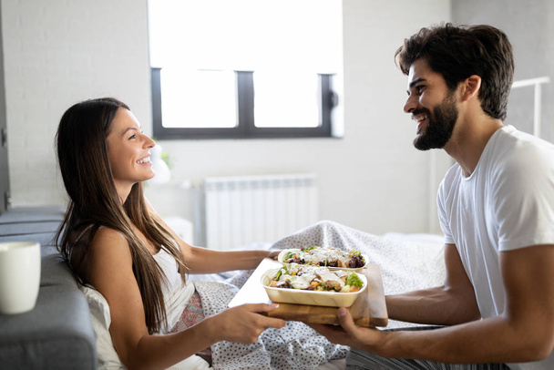 Romantic happy young couple having breakfast in bed - 写真・画像