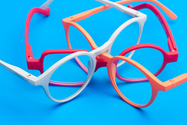 Colored glasses on plain background, modern glasses for fashion. - Фото, изображение