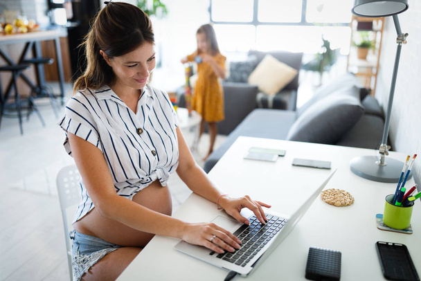 Young pregnant woman working from home. Career and pregnancy concept - Fotoğraf, Görsel