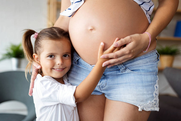 Beautiful pregnant woman with cute child, daughter. Pregnancy, family, love concept. - Photo, image