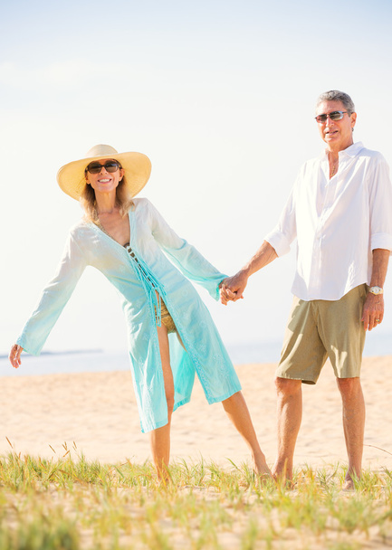 Пара средних лет наслаждается прогулкой по пляжу
 - Фото, изображение