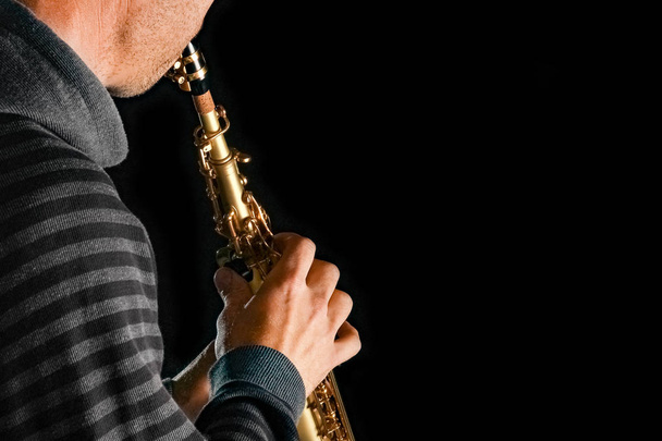 soprano saxophone in the hands of a guy on a black background - Foto, afbeelding