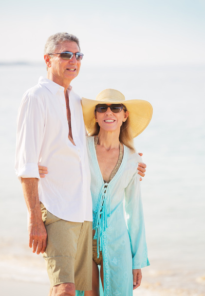 Пара средних лет наслаждается прогулкой по пляжу
 - Фото, изображение