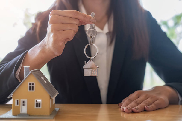 Agente de bienes raíces que tiene una llave y pidiendo al cliente un contrato para comprar, obtener un seguro o préstamo de bienes raíces o propiedades. - Foto, imagen