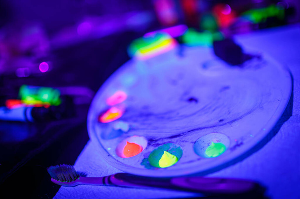 Різнокольоровий ультрафіолетовий флуоресцентний порошок і фарби на палітрі
 - Фото, зображення