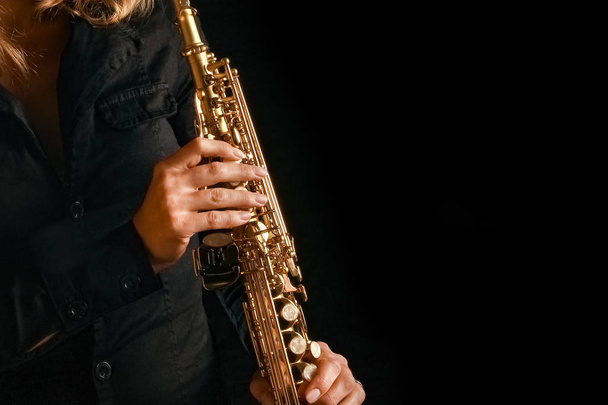 soprano saxophone in the hands of a girl on a black background - Valokuva, kuva