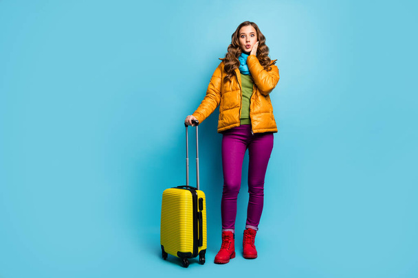 Full body photo of nice lady traveler hold rolling bag wait airport flight registration long big queue wear yellow overcoat blue scarf trousers shoes isolated blue color background - Foto, afbeelding