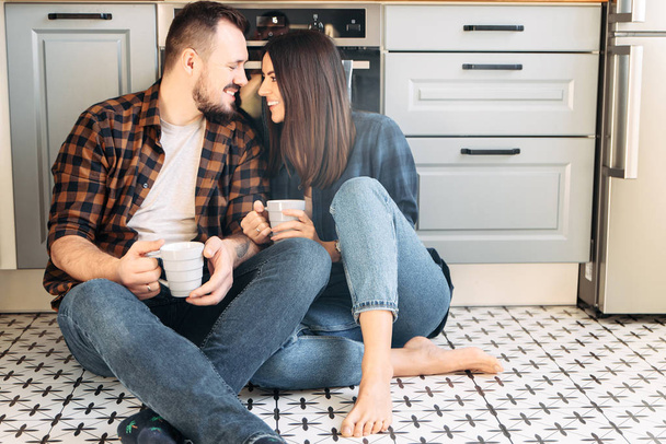 Happy couple sit on the floor with a cups - Фото, изображение