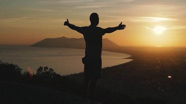 Reis. Een man staat op een berg en kijkt naar de zonsondergang.. - Video