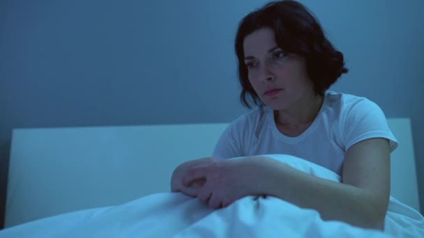 Lonely woman sitting in bed, sleepless at night upset with relationship problems - Felvétel, videó