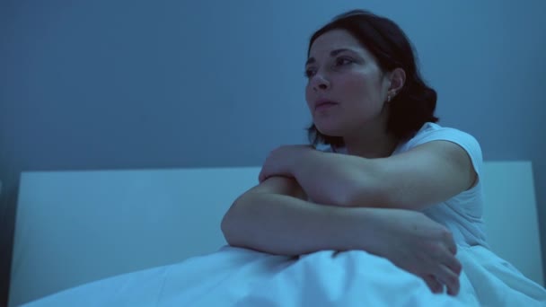Worried woman sitting in bed at night, sleepless wife waiting husband home alone - Кадри, відео