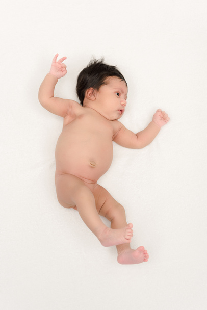 Draufsicht auf nacktes, birassisches Baby, das isoliert auf weißem Grund liegt  - Foto, Bild