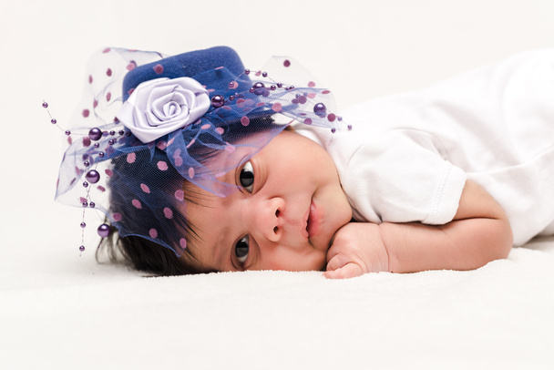 adorable bi-racial newborn baby in blue hat lying on white  - Fotó, kép