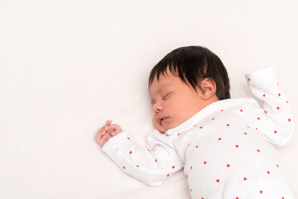 overhead view of cute bi-racial newborn in baby romper sleeping isolated on white  - Foto, imagen