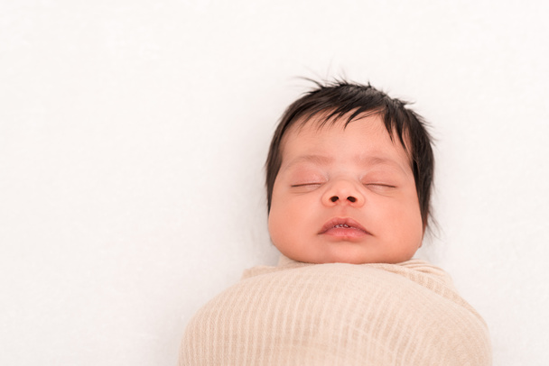 Blick von oben auf Mischlingsbaby in Decke gehüllt, schlafend isoliert auf weißem Grund  - Foto, Bild