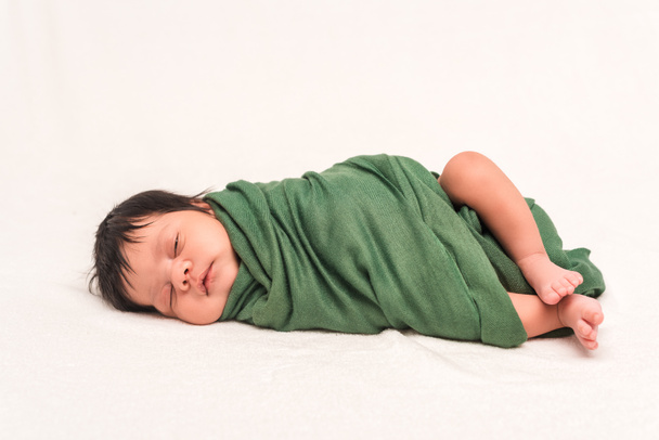 adorable bi-racial baby wrapped in green blanket sleeping isolated on white  - Photo, Image