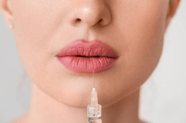 Young woman receiving filler injection against grey background, closeup - Foto, Imagen