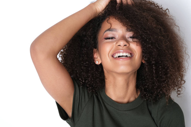 Jonge vitaliteit en mooie glimlach op studio shoot. Vrij jong afro-0american model in groene jurk. - Foto, afbeelding