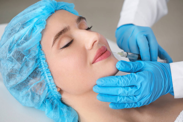 Young woman receiving filler injection in beauty salon - Fotoğraf, Görsel