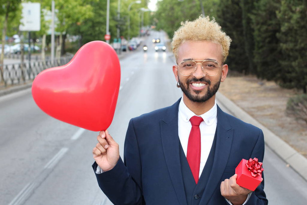 κοντινό πορτρέτο του όμορφου νεαρού άνδρα με κοστούμι και μπαλόνι σε σχήμα καρδιάς στο δρόμο - Φωτογραφία, εικόνα