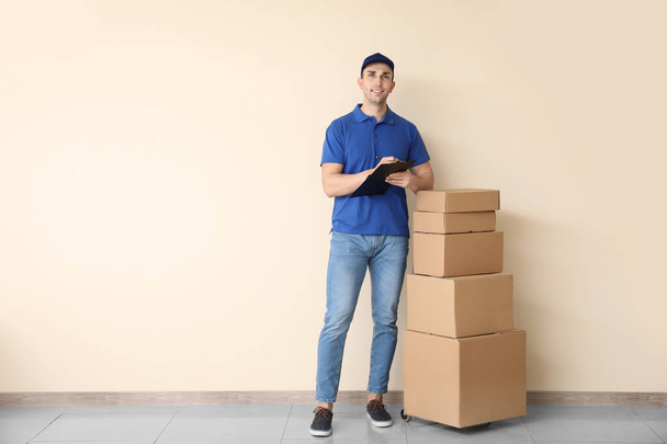 Delivery man with boxes near color wall - Photo, Image