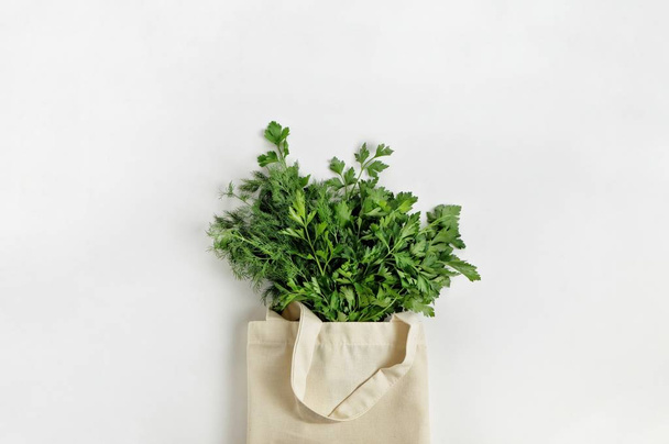 Un manojo de perejil verde orgánico fresco y eneldo en una bolsa reutilizable de algodón sobre un fondo blanco. Comida saludable, productos orgánicos, estilo de vida ecológico, concepto de cero residuos. Vista superior, espacio de copia
. - Foto, Imagen