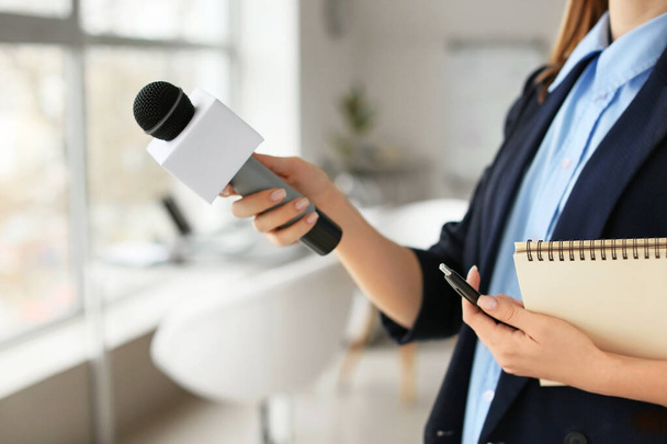Vrouwelijke journalist met microfoon heeft een interview in het kantoor - Foto, afbeelding