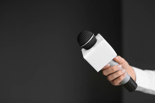 Mão de jornalista com microfone no fundo escuro
 - Foto, Imagem