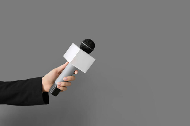 Mão de jornalista com microfone em fundo cinza
 - Foto, Imagem