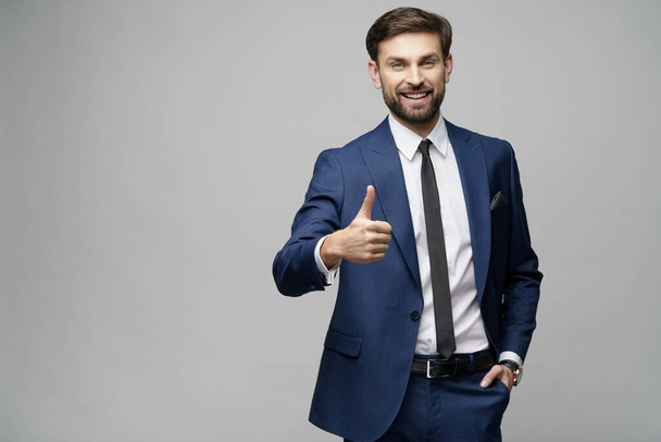 young business man going thumb up on grey background - Foto, immagini