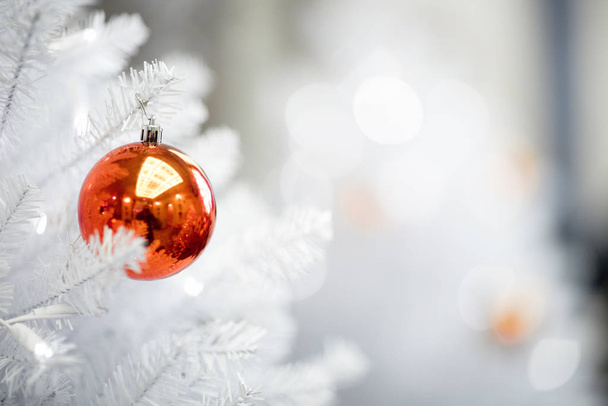 κόκκινη μπάλα κρέμεται από ένα διακοσμημένο χριστουγεννιάτικο δέντρο - Φωτογραφία, εικόνα