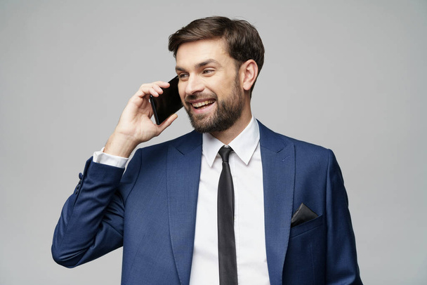 businessman talking on the phone isolated over grey background - Foto, afbeelding
