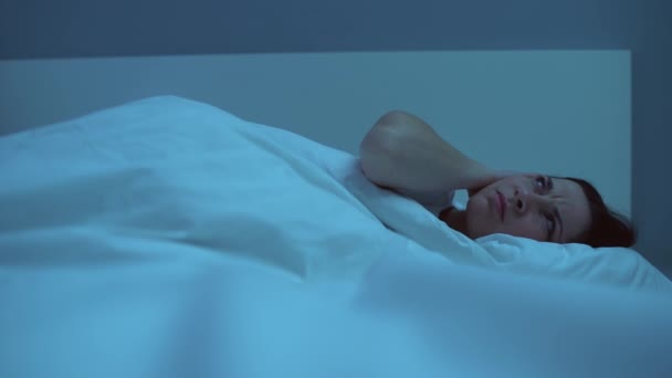 Annoyed woman sleepless in bed, covering ears with pillow from noisy neighbors - Filmagem, Vídeo