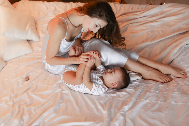 Mom plays and has fun on the bed with her little son - Foto, Imagen