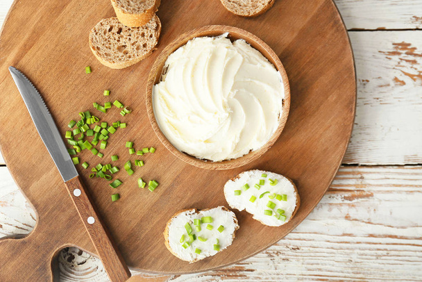 Fresh bread with tasty cream cheese and green onions on table - Photo, Image