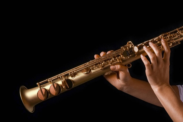 soprano saxophone in the hands of a girl on a black background - Zdjęcie, obraz