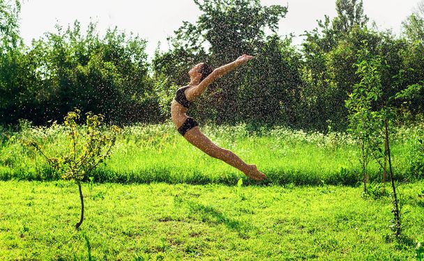Young beautiful woman jumping in the water drops. - 写真・画像