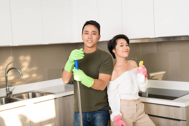 Счастливая молодая азиатская пара убирает кухню вместе
 - Фото, изображение
