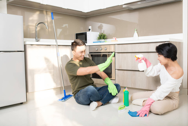 Ama de casa y su marido limpiando casa y divirtiéndose juntos. Servicio de limpieza, limpieza del hogar y concepto de servicio de limpieza
 - Foto, Imagen
