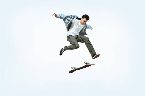 Кавказький молодий скейтбордист їде ізольованим на білому тлі. - Фото, зображення