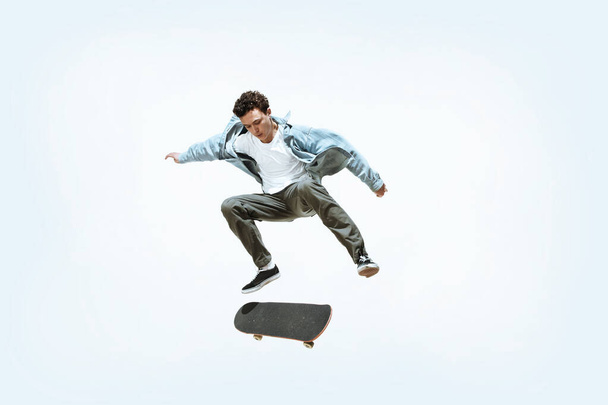 Caucasian young skateboarder riding isolated on a white background - Фото, изображение
