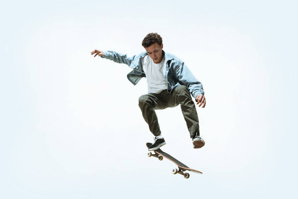 Caucasian young skateboarder riding isolated on a white background - Zdjęcie, obraz