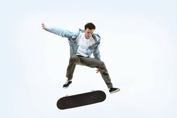 Caucasian young skateboarder riding isolated on a white background - 写真・画像