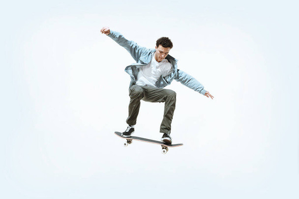 Caucasian young skateboarder riding isolated on a white background - Fotó, kép