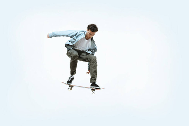Caucasian young skateboarder riding isolated on a white background - Foto, Bild